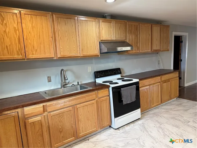 a kitchen with granite countertop a sink stainless steel appliances and cabinets