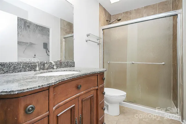 a bathroom with a granite countertop shower sink vanity and toilet