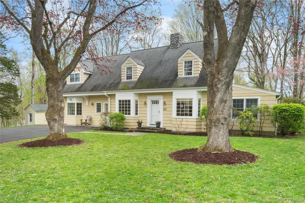 a front view of a house with a garden and trees