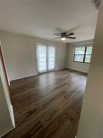 an empty room with wooden floor chandelier and windows