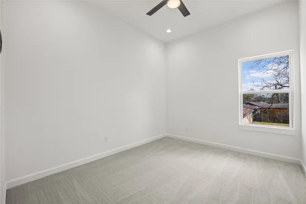 an empty room with a window and a ceiling fan