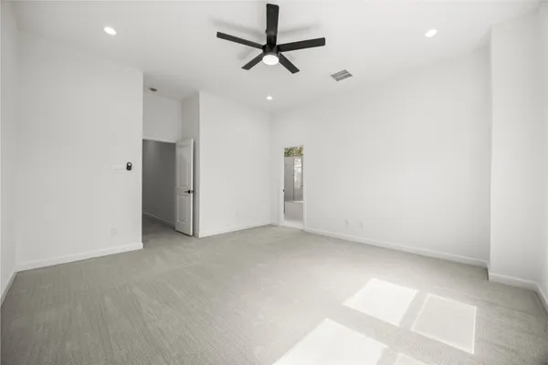 an empty room with a ceiling fan and carpet