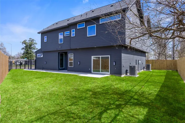 a brick house with a big yard plants and big trees