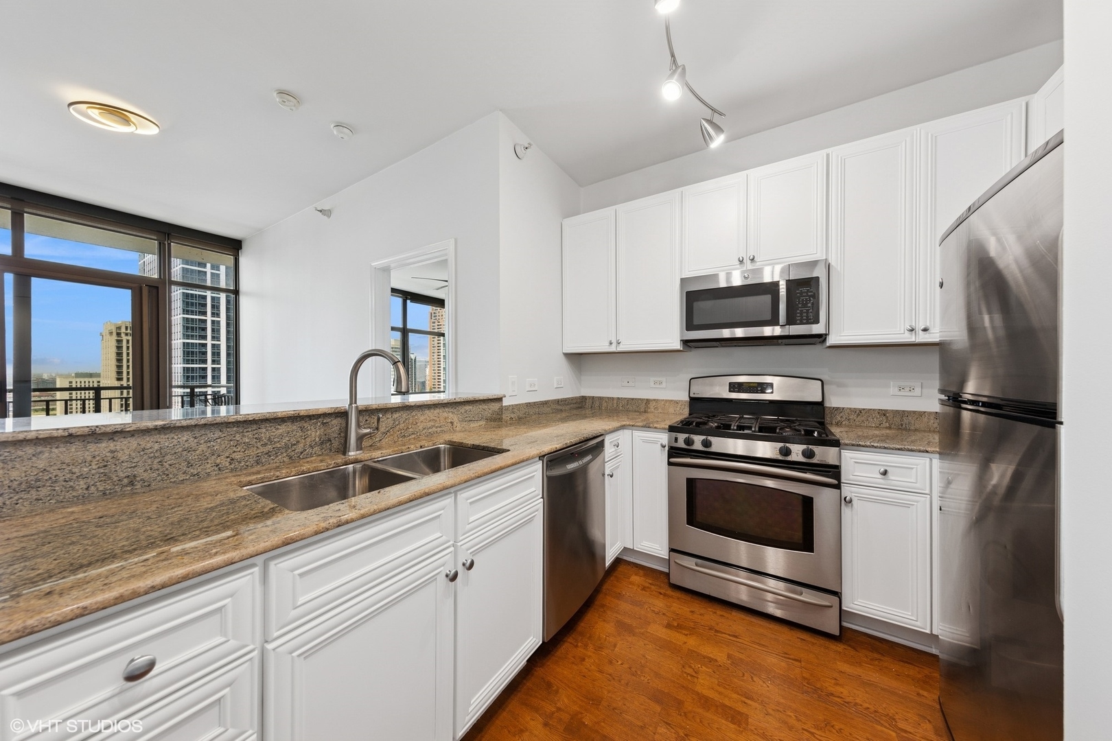 233 East 13th Street, Unit 2210 Chicago, IL 60605 - Photo 3 of 28 a kitchen with stainless steel appliances granite countertop a sink a stove a refrigerator a microwave oven with cabinets and wooden floor