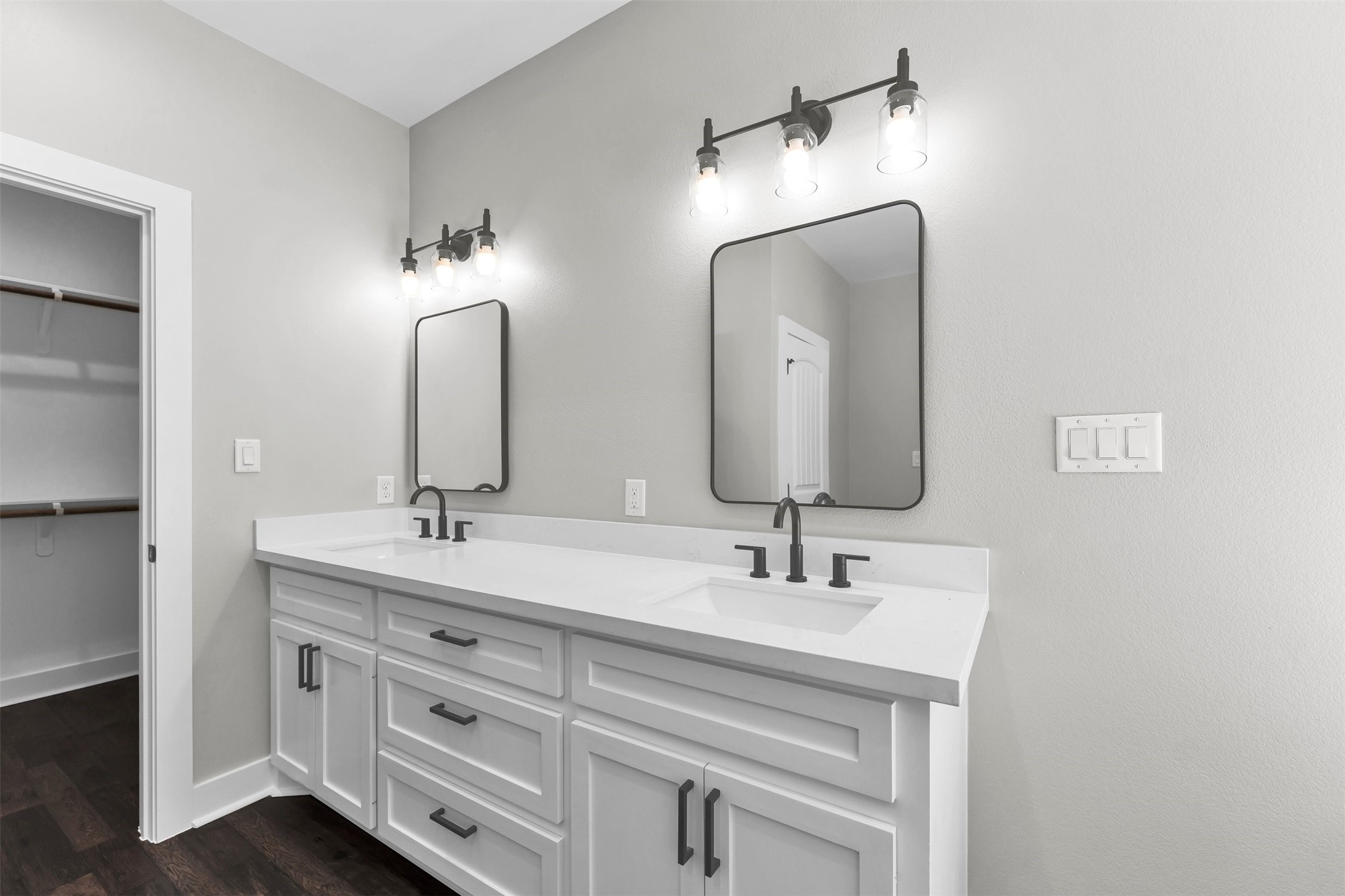 1087 Jones Road New Waverly, TX 77358 - Photo 19 of 44 Elegant dual-sink vanity with sleek black fixtures, modern mirrors, and ample storage, complemented by stylish lighting and adjacent to a walk-in closet.