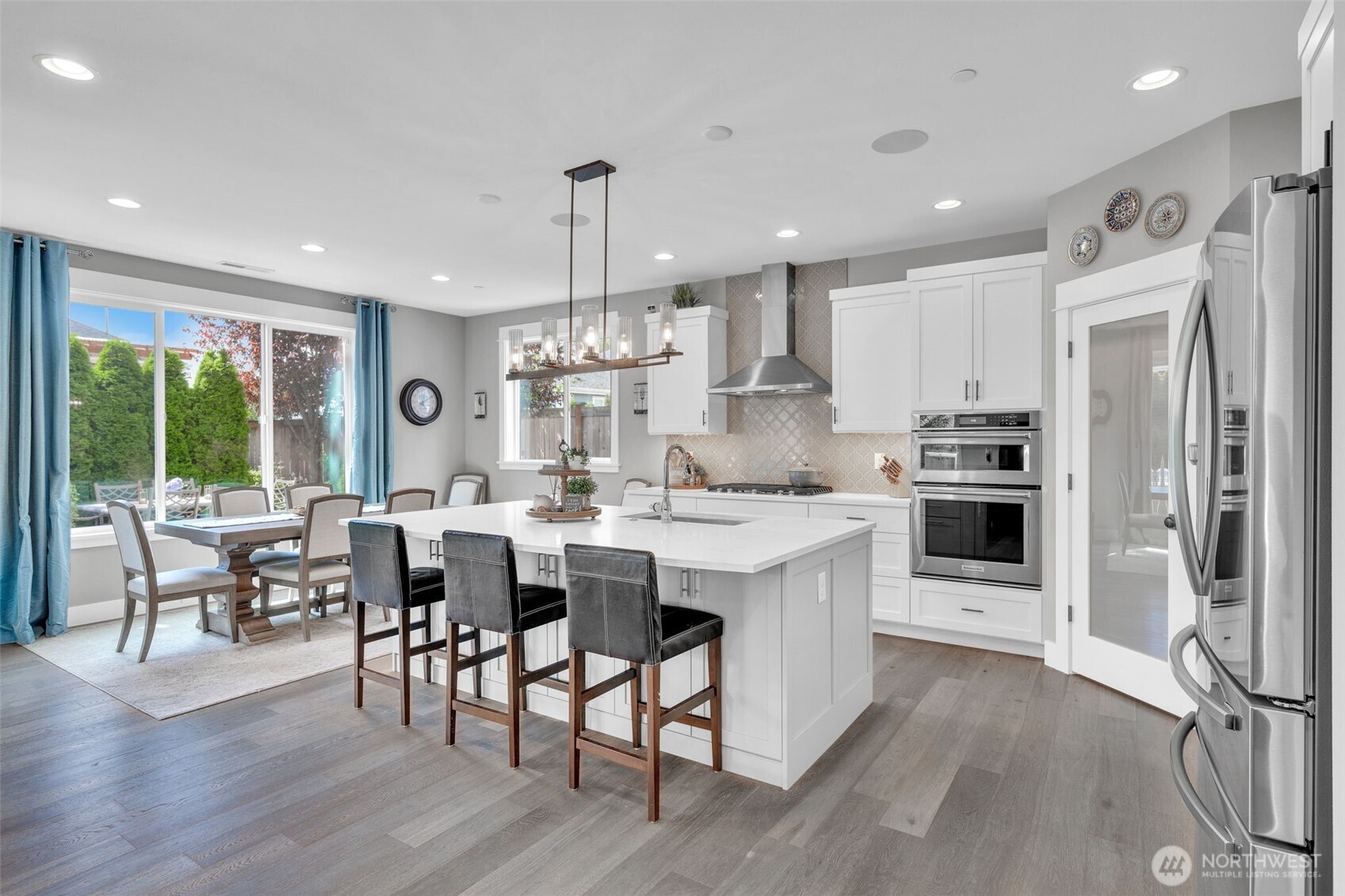 23216 9th Avenue Southeast Bothell, WA 98021 - Photo 10 of 40 a open kitchen with stainless steel appliances granite countertop a refrigerator a stove a sink a dining table and chairs with wooden floor