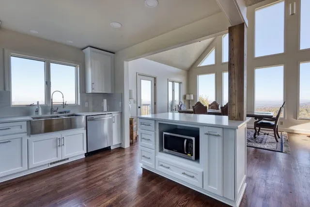 a kitchen with stainless steel appliances granite countertop a refrigerator a stove a sink and a dining table with wooden floor