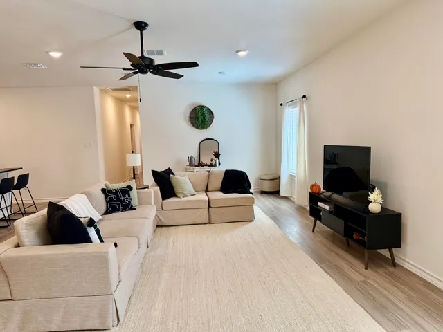 a living room with furniture a flat screen tv and a window