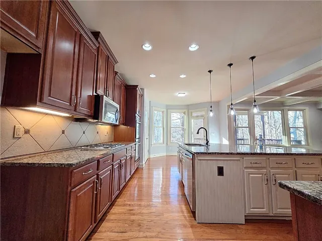 a kitchen with stainless steel appliances granite countertop wooden cabinets a oven and a sink