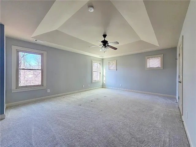 an empty room with windows and chandelier fan