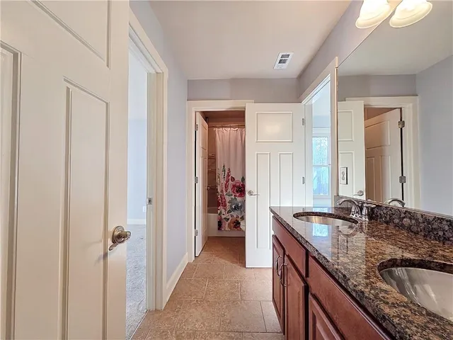 a en suite bathroom with a granite countertop sink and a mirror