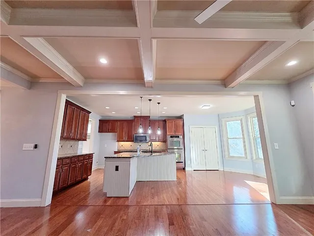a kitchen with stainless steel appliances kitchen island wooden floors granite counter tops and a view of living room