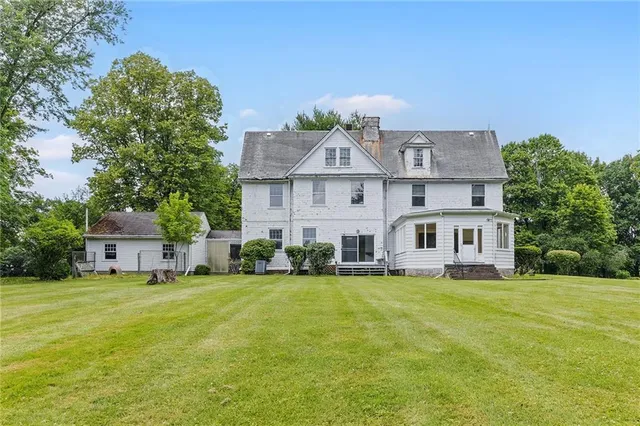 a view of a house with a big yard and large trees