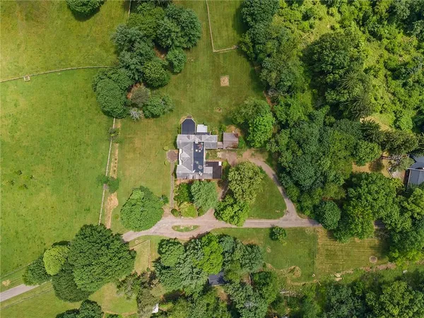 an aerial view of residential house with outdoor space and trees all around