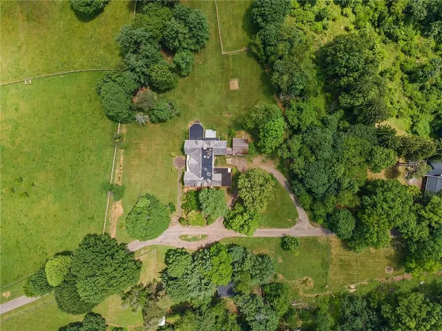 an aerial view of residential house with outdoor space and trees all around