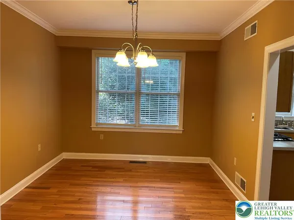 a view of a room with wooden floor chandeliers and kitchen view