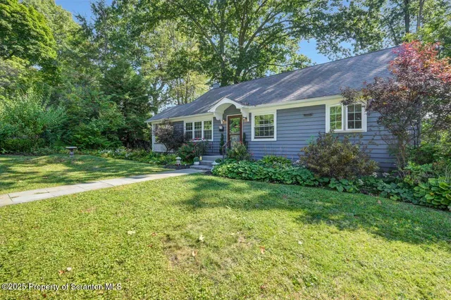 a view of a house next to a big yard and large trees