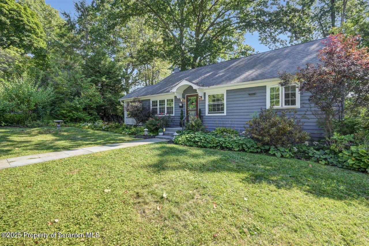 a view of a house next to a big yard and large trees