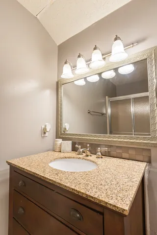 a bathroom with a granite countertop sink and a mirror
