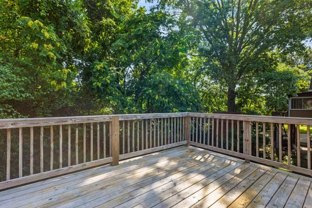 a balcony with wooden floor and trees in the back