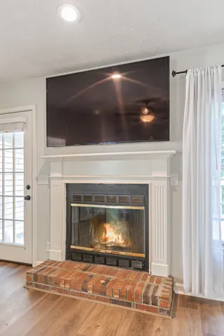 a view of a livingroom with a fireplace a ceiling fan and wooden floor