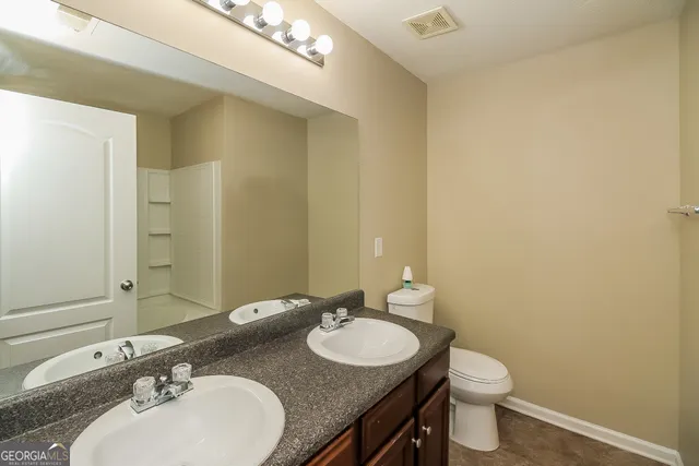 a bathroom with a double vanity sink toilet and a mirror