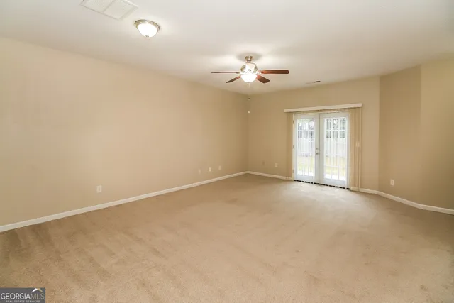 an empty room with windows and chandelier fan