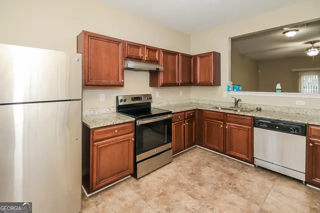 a kitchen with stainless steel appliances granite countertop a refrigerator a stove a sink and a microwave