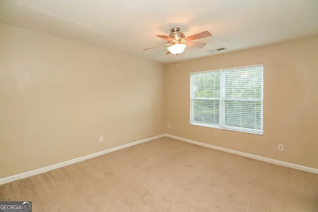 en empty room with windows and chandelier fan