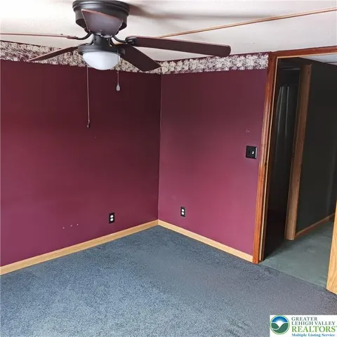a view of a house with large tree and covered with wooden fence