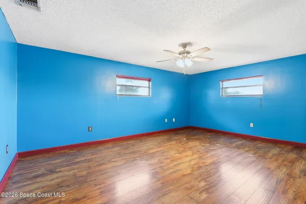 a view of an empty room with chandelier fan and a window