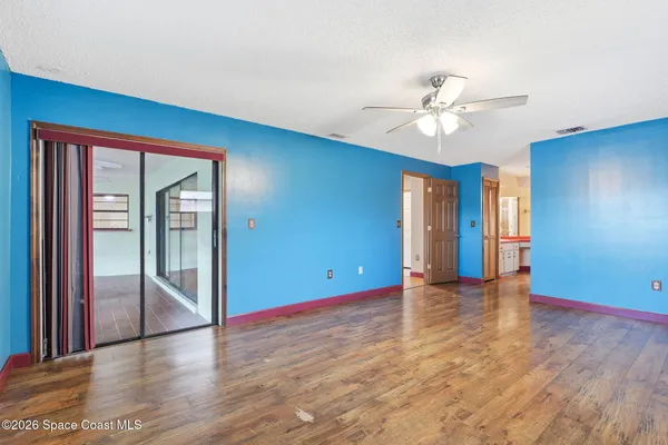 a view of an empty room with window and wooden floor