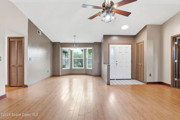 a view of an empty room with window and wooden floor