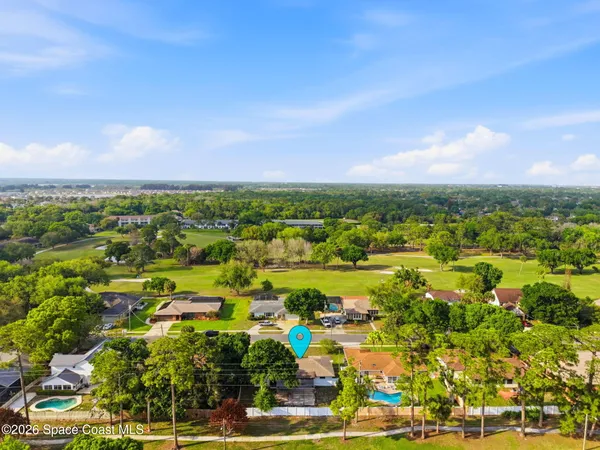 an aerial view of residential houses with outdoor space and trees