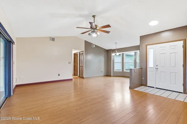 a view of an empty room with window and wooden floor