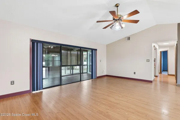 a view of an empty room with window and wooden floor