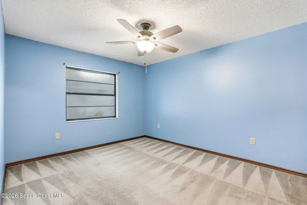 an empty room with windows and fan