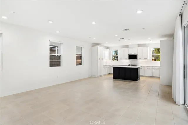 a large white kitchen with kitchen island a sink stainless steel appliances and cabinets