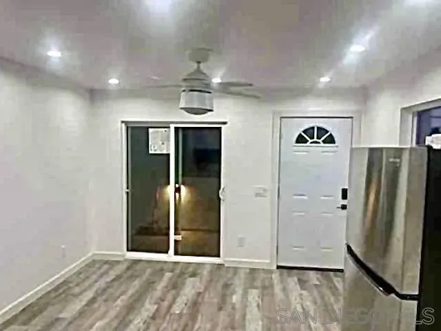 an empty room with wooden floor and a ceiling fan