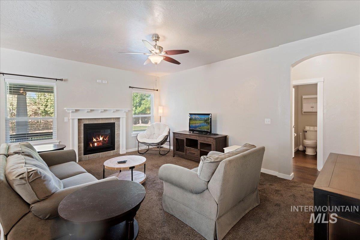 401 East Joshua Tree Drive Meridian, ID 83646 - Photo 7 of 32 Carpeted living room with arched walkways, a ceiling fan, a tile fireplace, and healthy amount of natural light