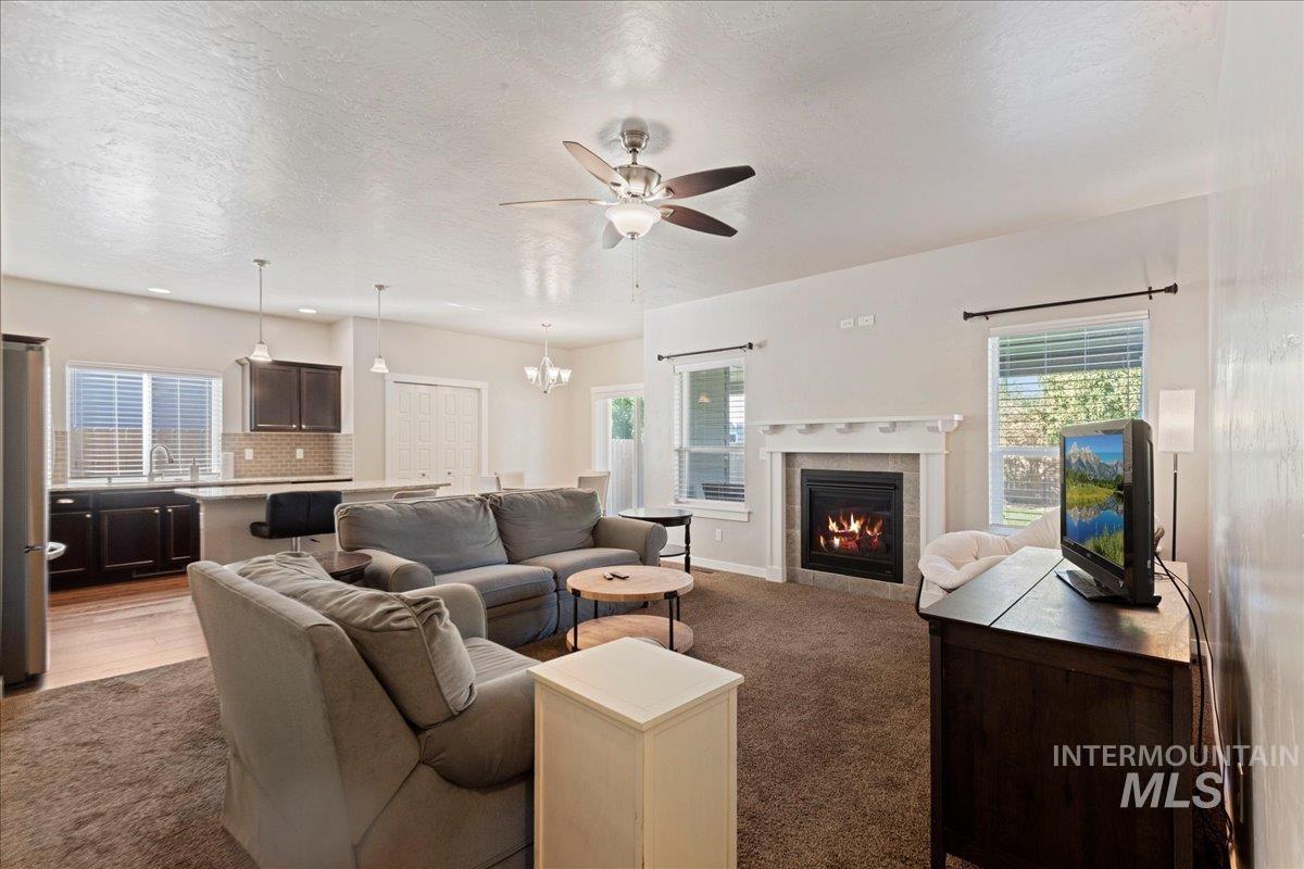 401 East Joshua Tree Drive Meridian, ID 83646 - Photo 8 of 32 Carpeted living room featuring ceiling fan, healthy amount of natural light, a tile fireplace, a chandelier, and a textured ceiling