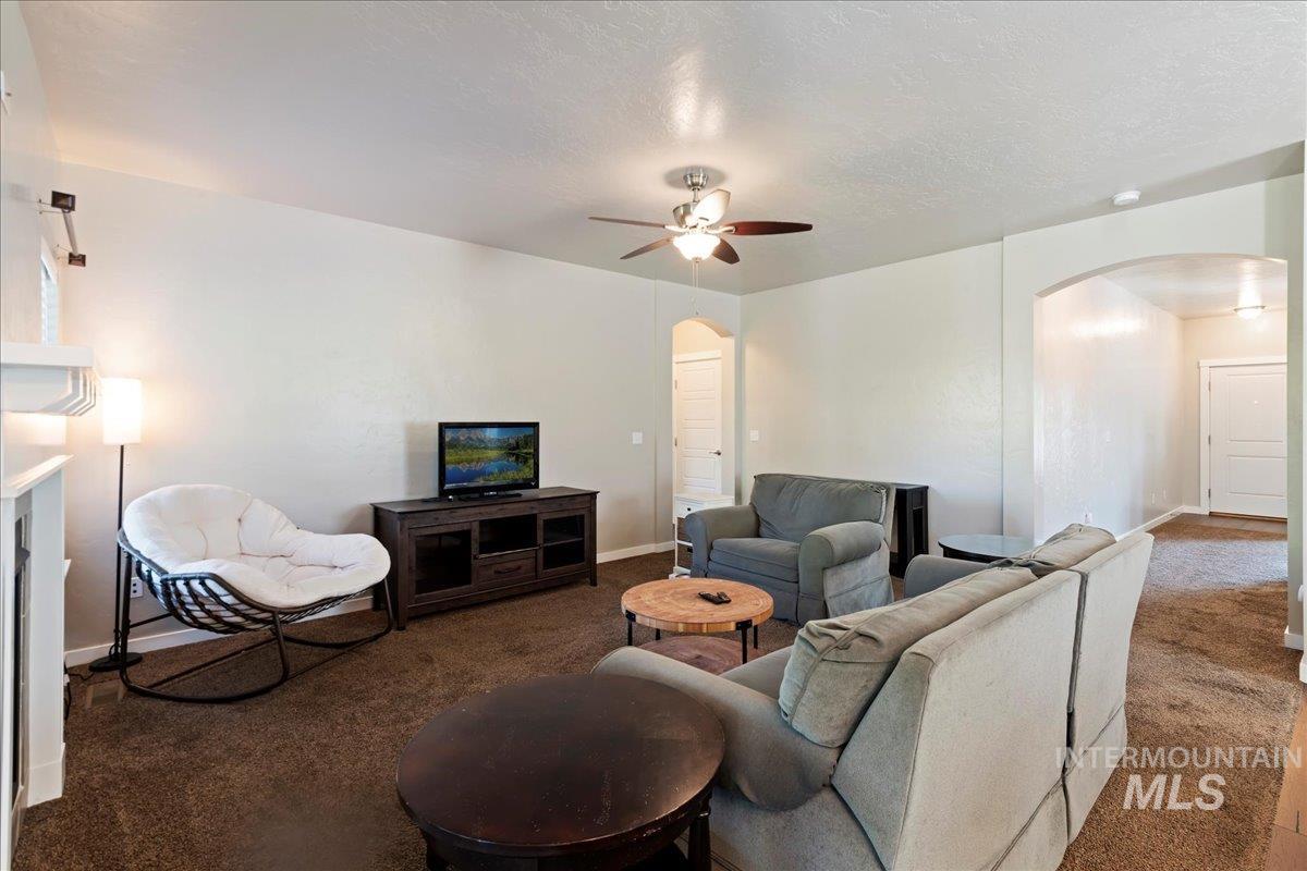 401 East Joshua Tree Drive Meridian, ID 83646 - Photo 9 of 32 Living room featuring arched walkways, carpet flooring, a ceiling fan, and a textured ceiling