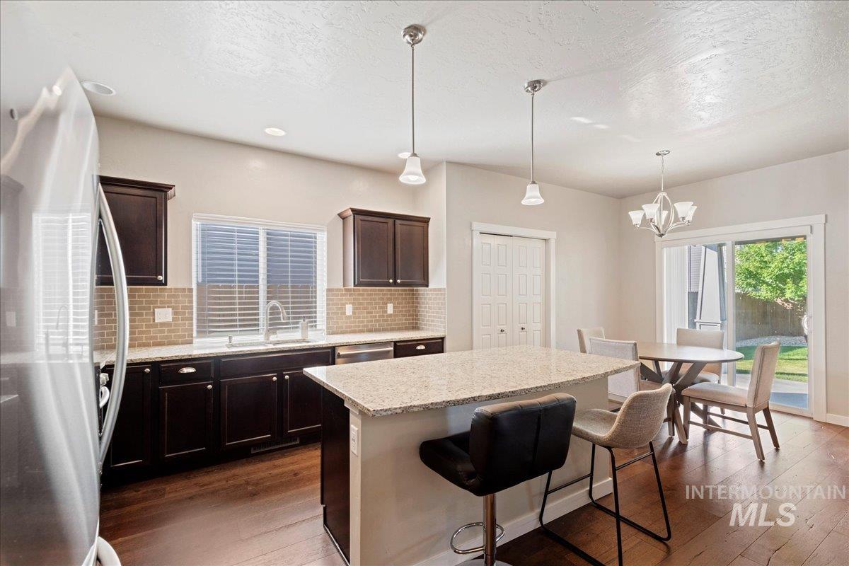 401 East Joshua Tree Drive Meridian, ID 83646 - Photo 10 of 32 Kitchen with freestanding refrigerator, decorative backsplash, dark wood finished floors, a kitchen breakfast bar, and a kitchen island