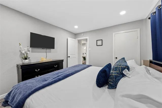 a bedroom with a bed a flat screen tv and a mirror