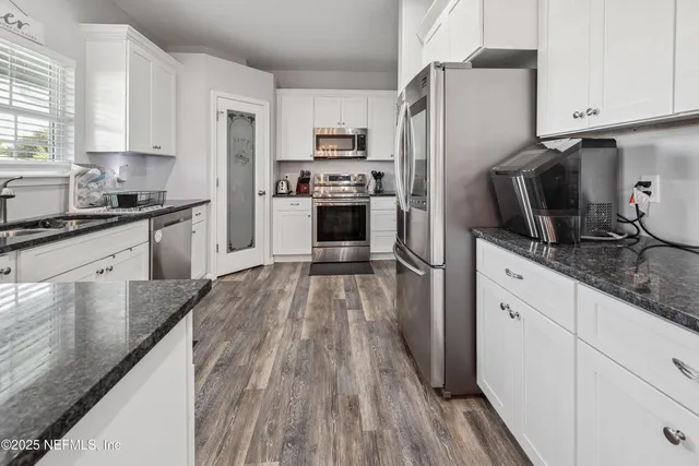 a kitchen with stainless steel appliances a refrigerator sink and wooden floor