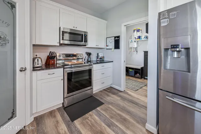a kitchen with stainless steel appliances granite countertop a sink and cabinets with wooden floor