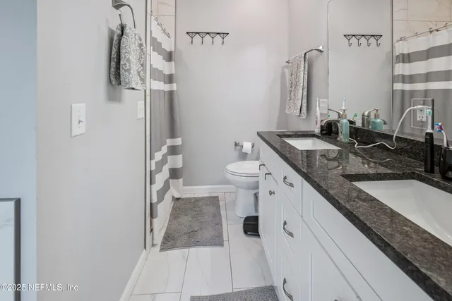 a bathroom with a granite countertop sink a toilet and bathtub