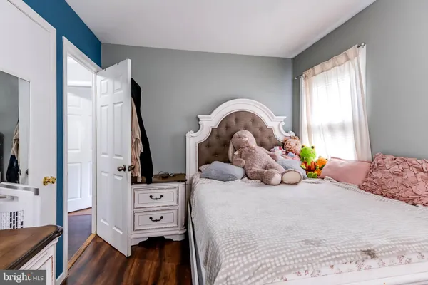 a bedroom with a bed next to a large window with wooden floor