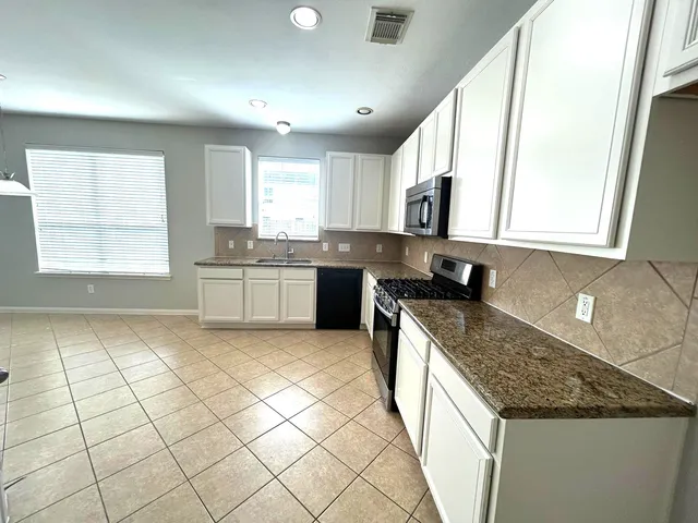 a kitchen with stainless steel appliances granite countertop a sink and dishwasher a stove top oven with wooden floor