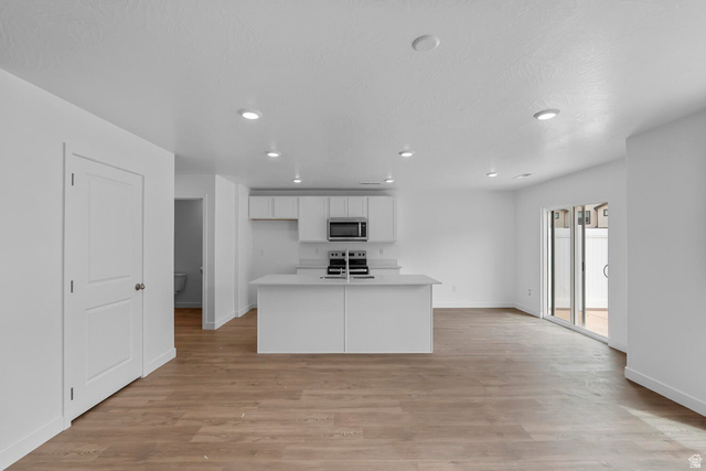 2133 Wolverine Way, Unit 2440 Washington, UT 84780 - Photo 5 of 39 Open-concept living area featuring wood-finish flooring, recessed lighting, and a contemporary kitchen with white cabinetry and an island